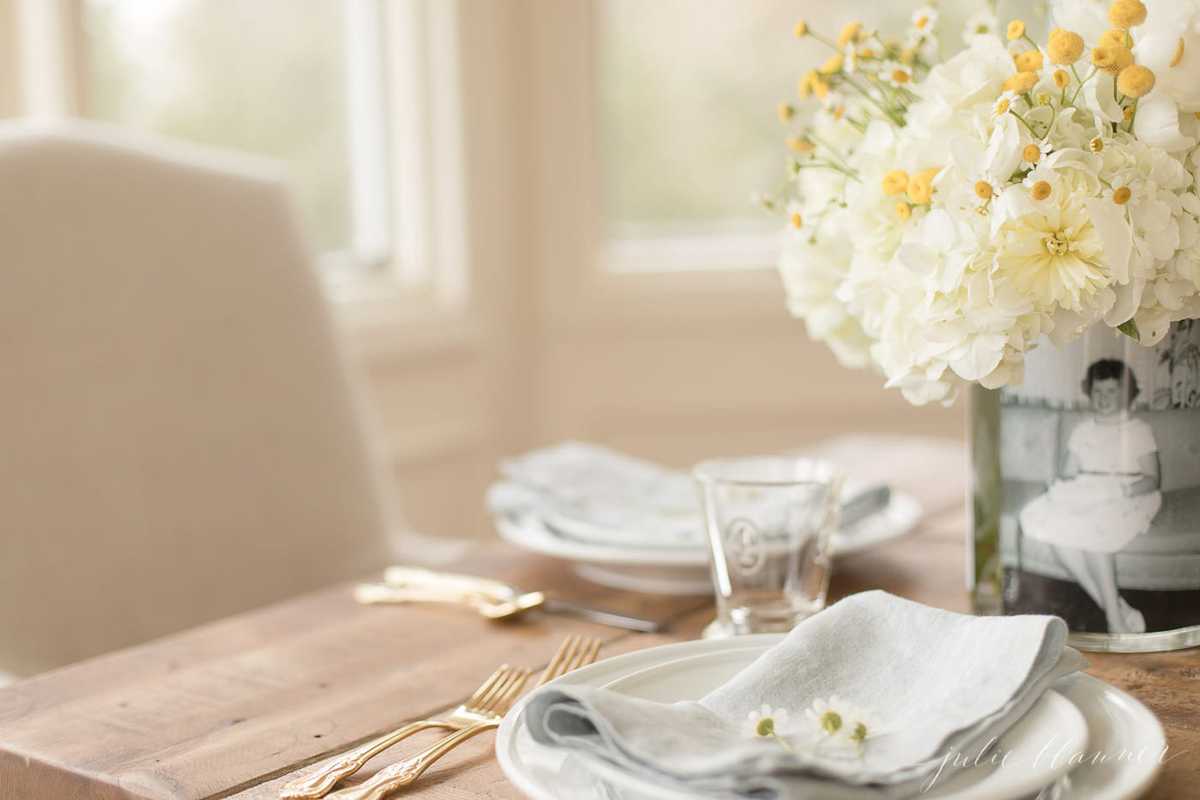 mother's day table decor of a vase of flowers with a vintage photograph on a table set for brunch.