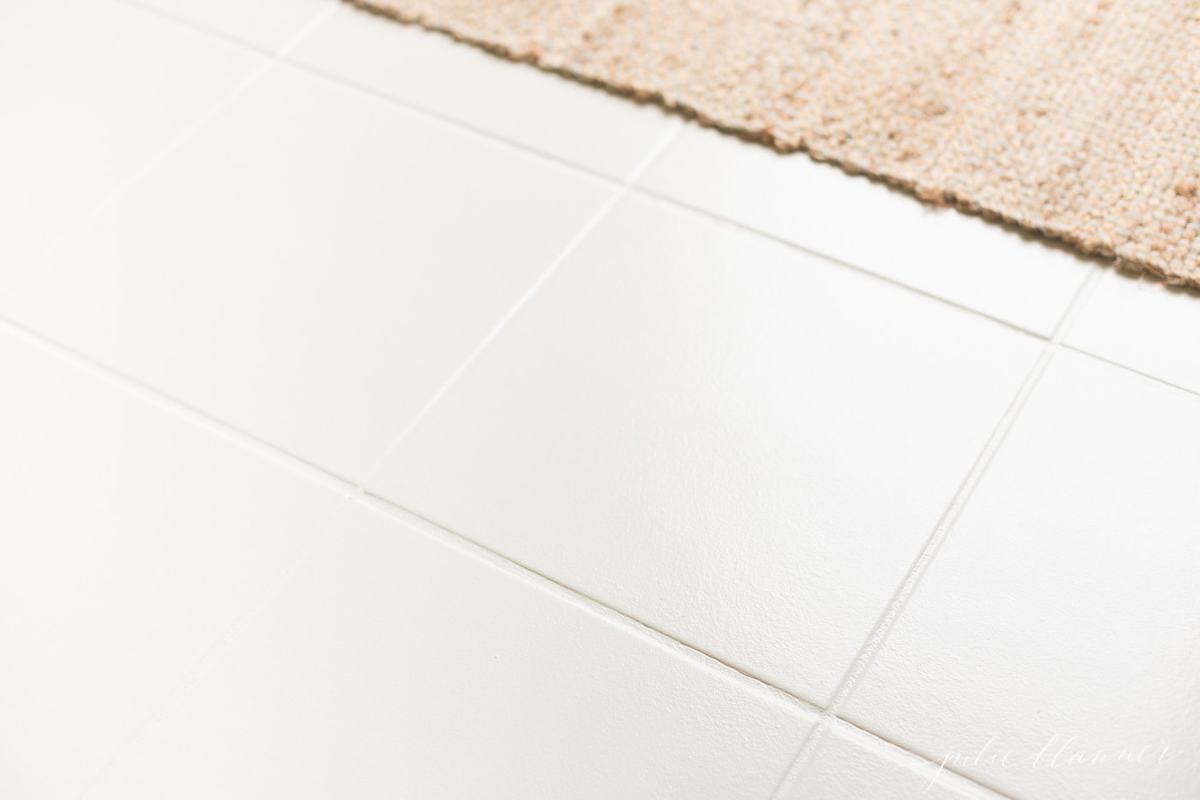 A white tile floor with a jute rug in the background