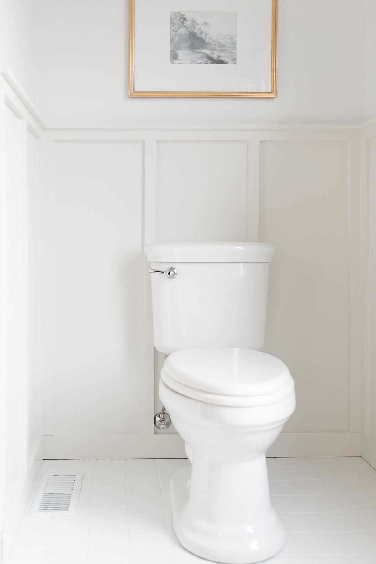 A small bathroom with painted tile and gray board and batten on the walls