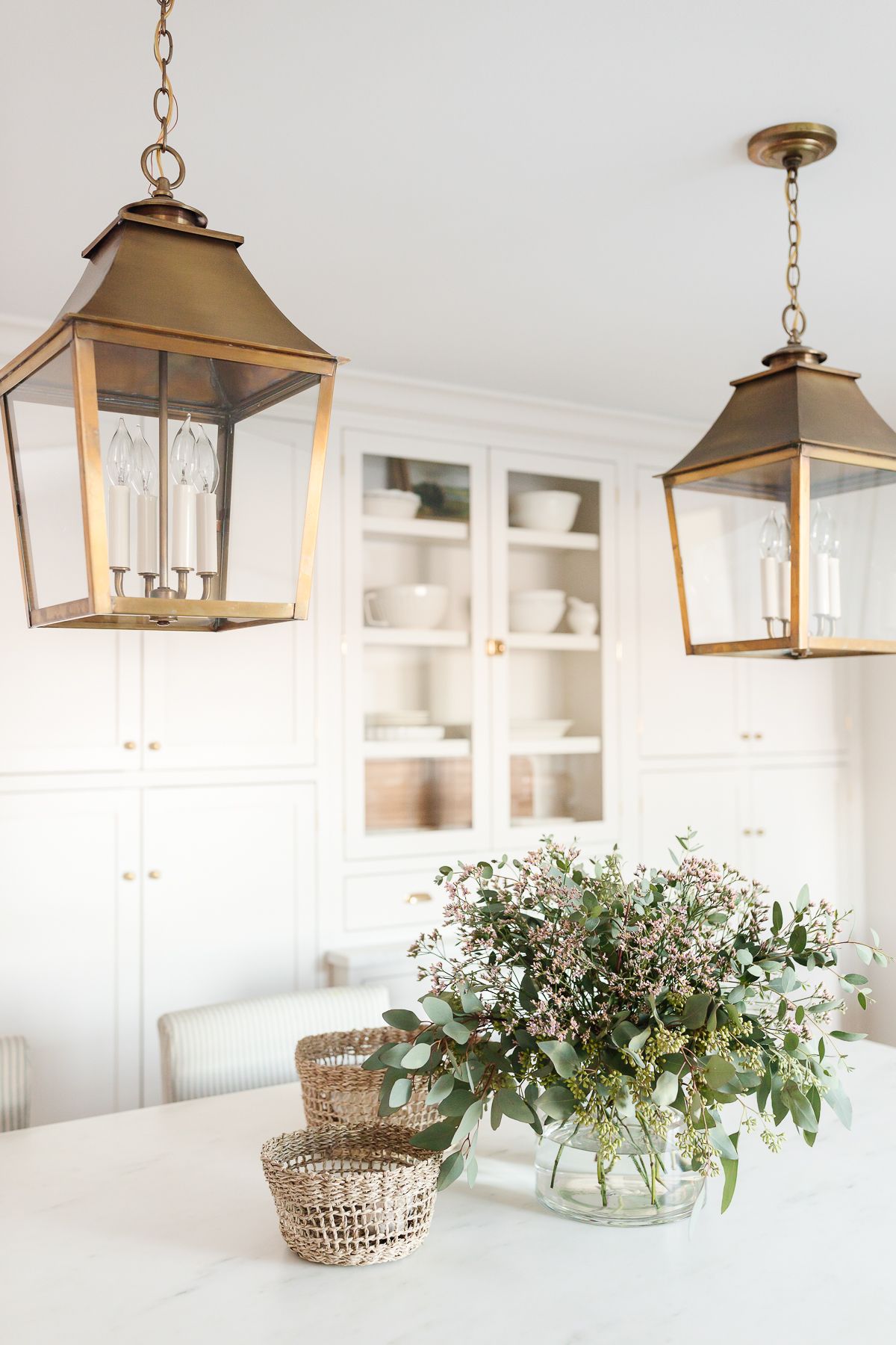 Two brass lantern pendants hanging over a kitchen island