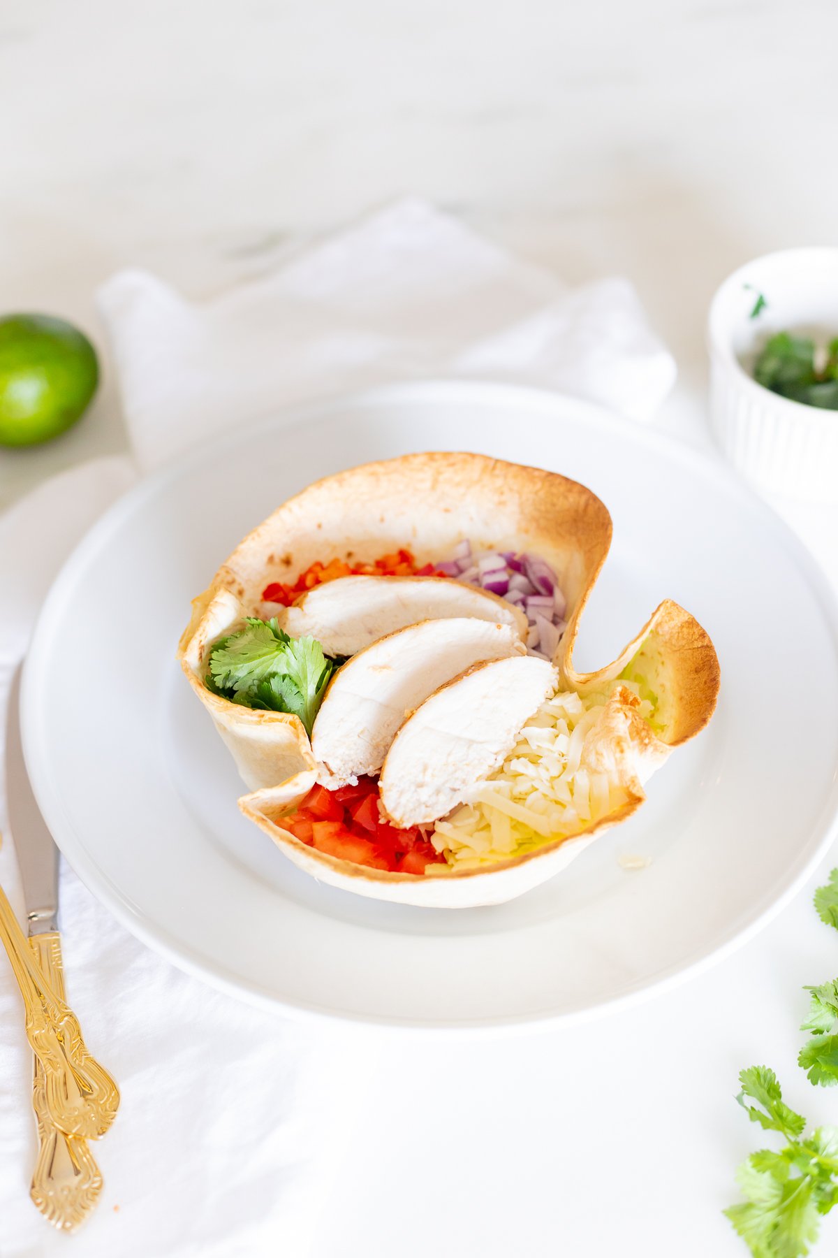 taco salad in tortilla bowl with gold utensils