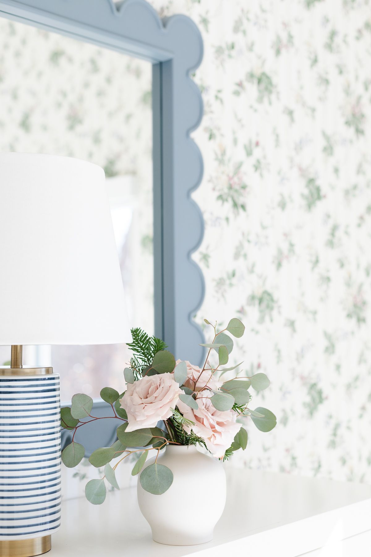 Pink roses in a small white ceramic flower vase.