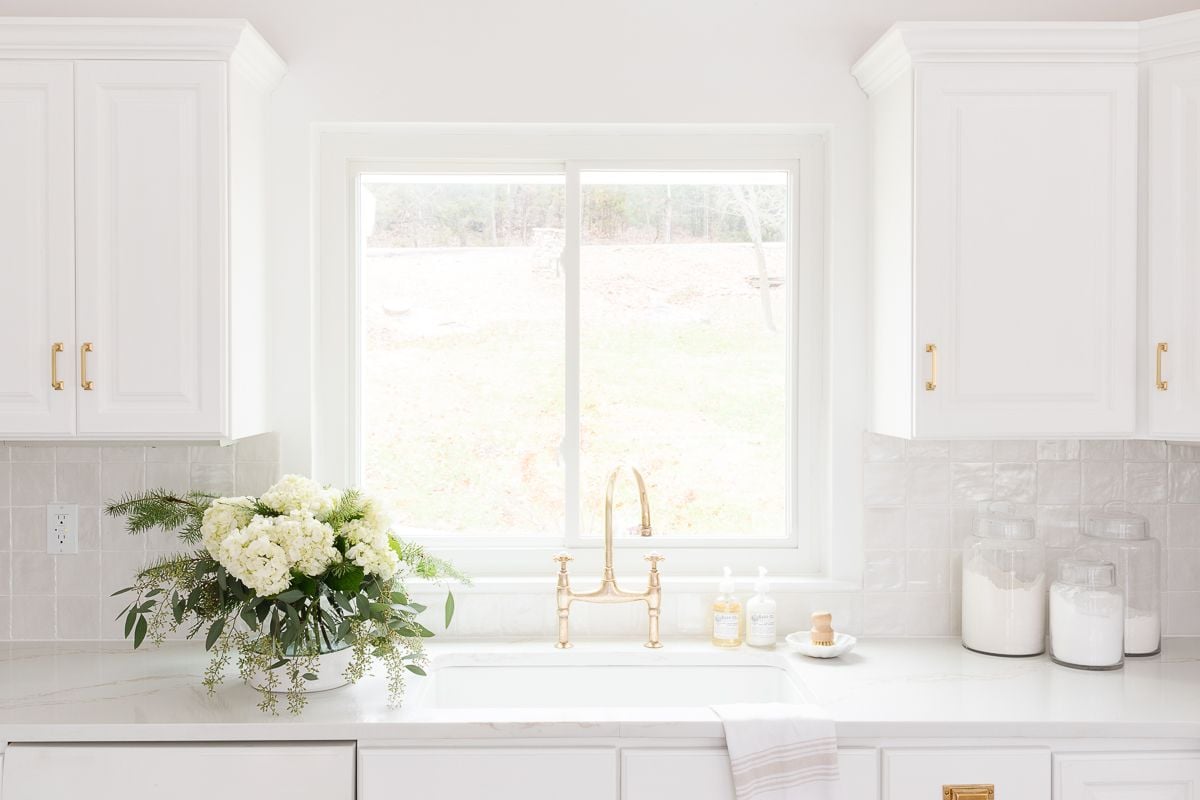 White flowers in a glass flower vase in a white kitchen.