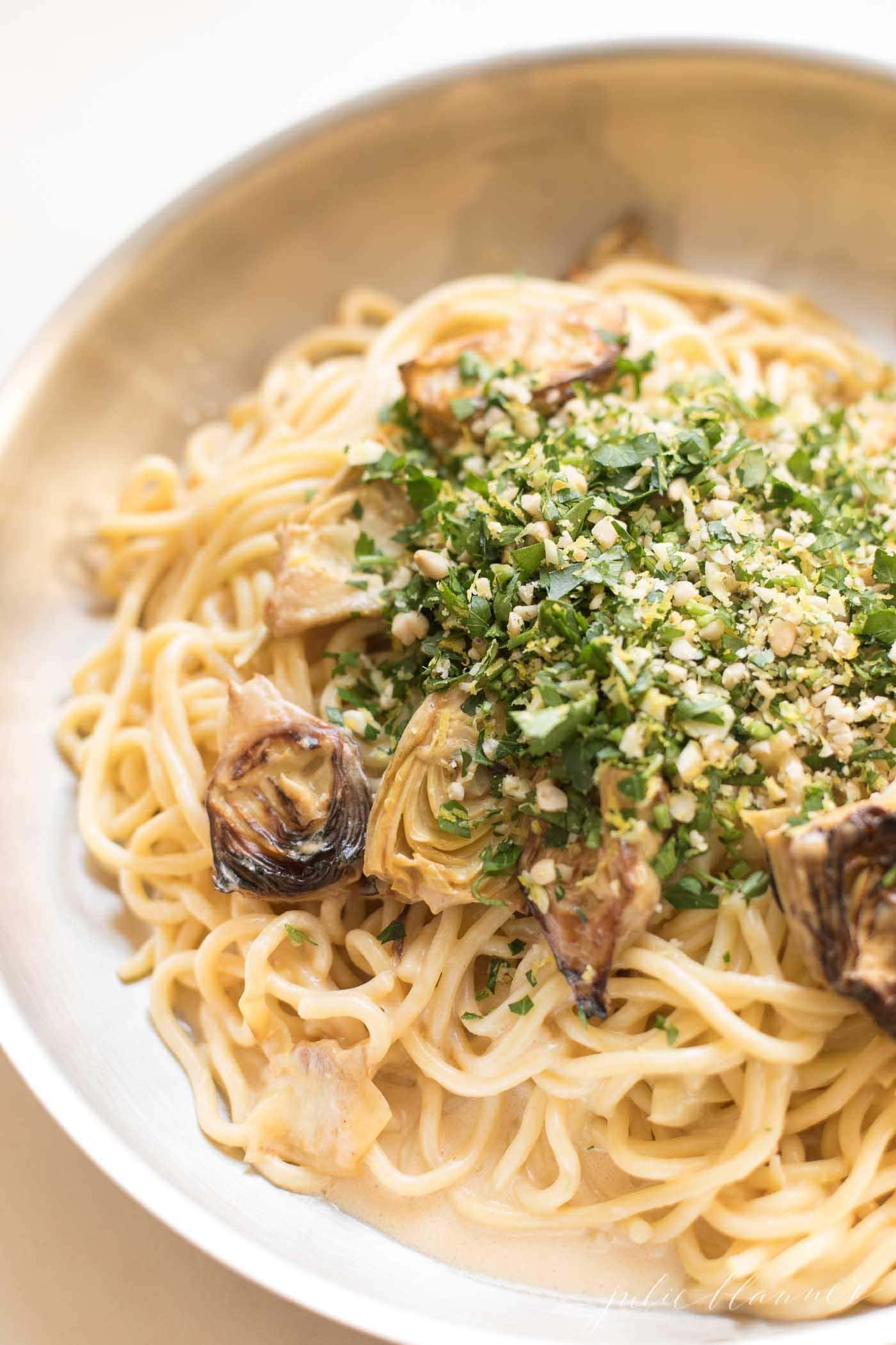 spaghetti in a skillet with artichokes topped with gremolata
