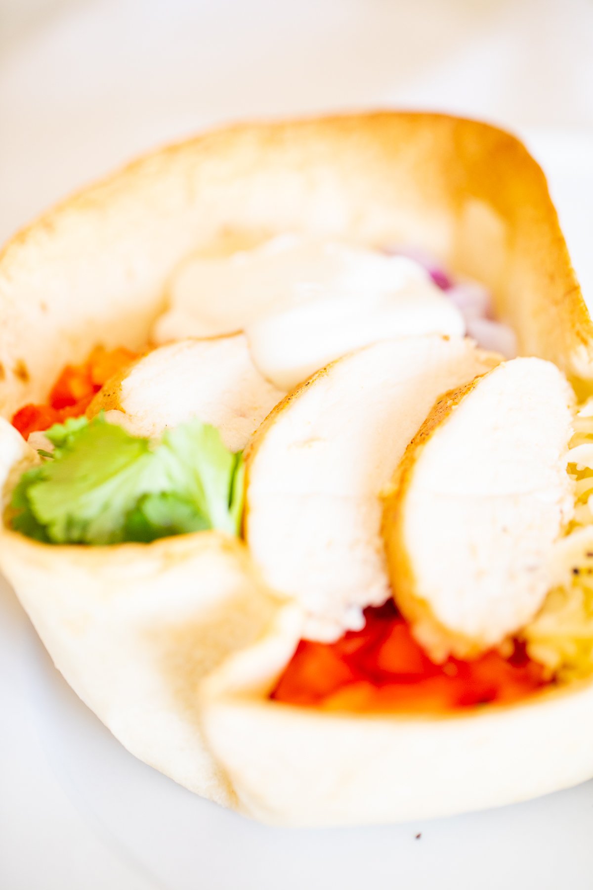 A chicken taco salad in a homemade tortilla bowl on a white plate.