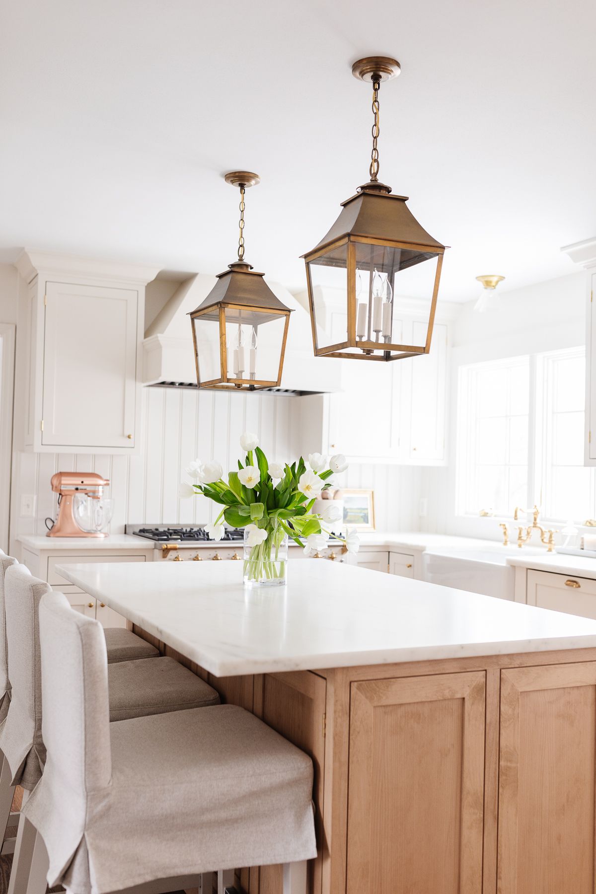 Two brass lantern pendants hanging over a light wood kitchen island