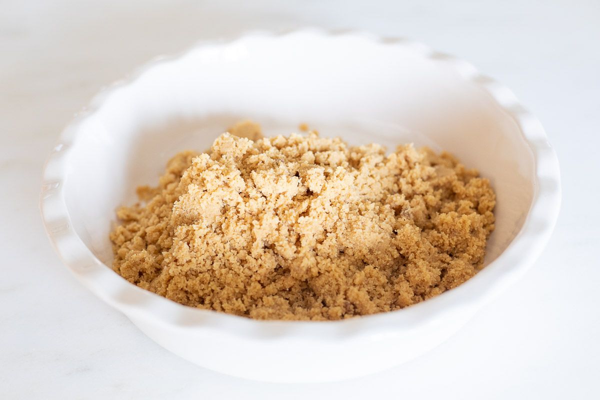 Ingredients for a no bake shortbread crust in a white ruffled ceramic pie dish
