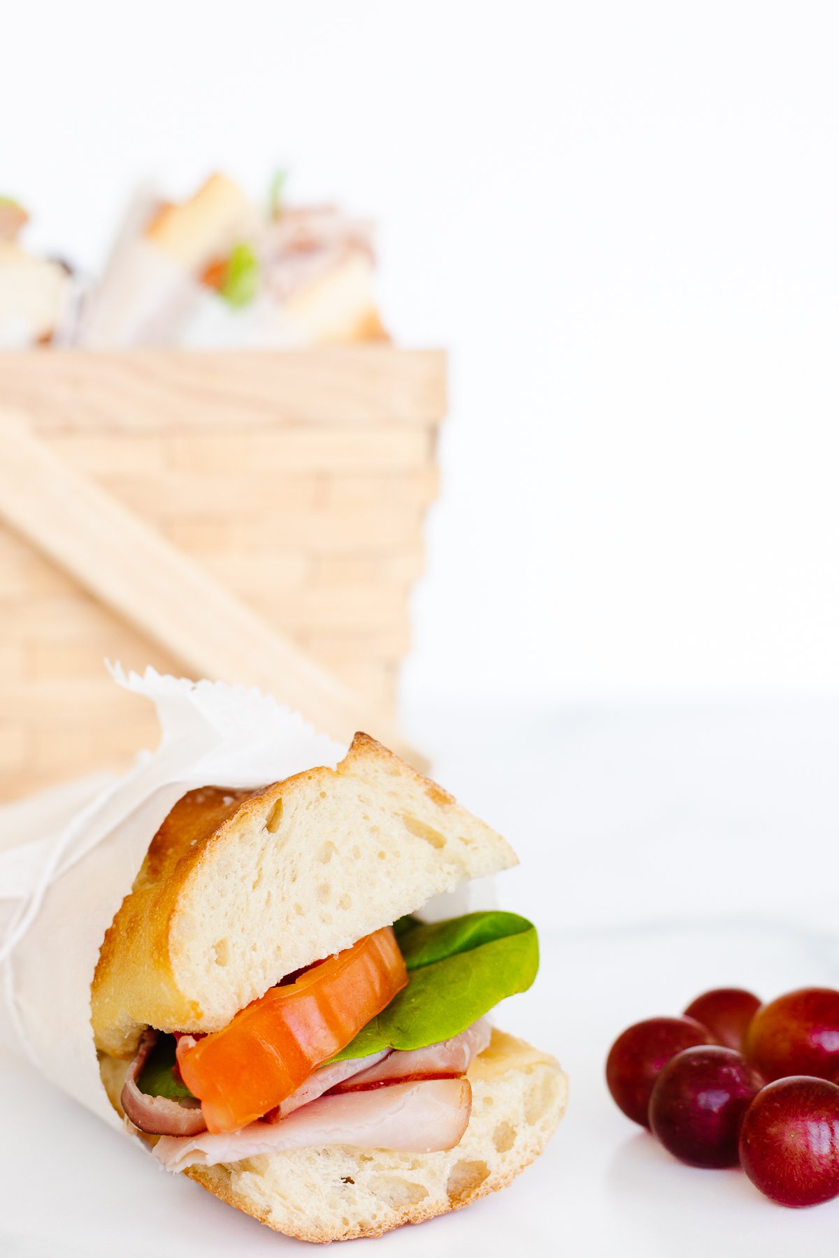 A sandwich and grapes at a picnic.