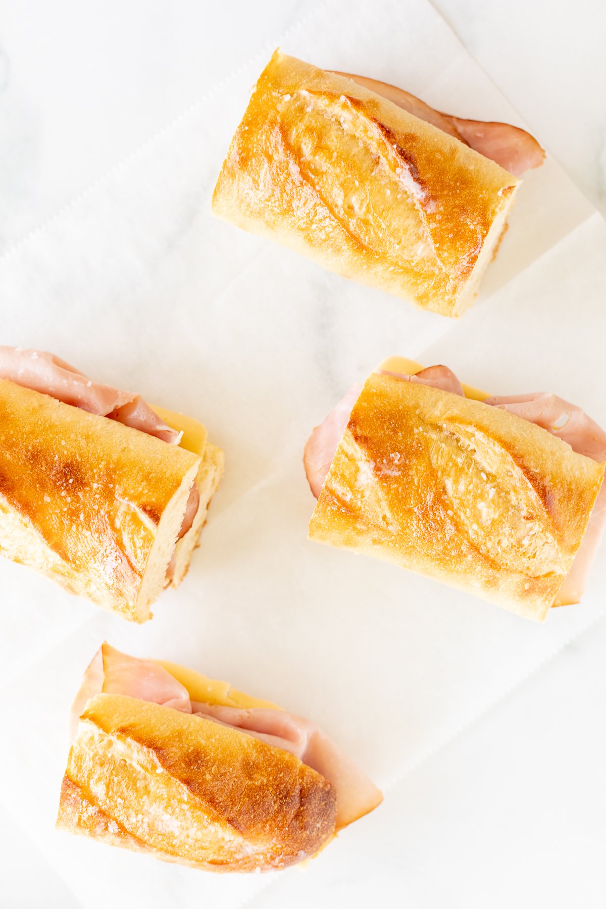 Four picnic sandwiches on a white sheet of paper.