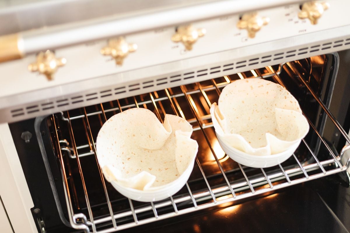 Two taco bowl shells baking in an oven