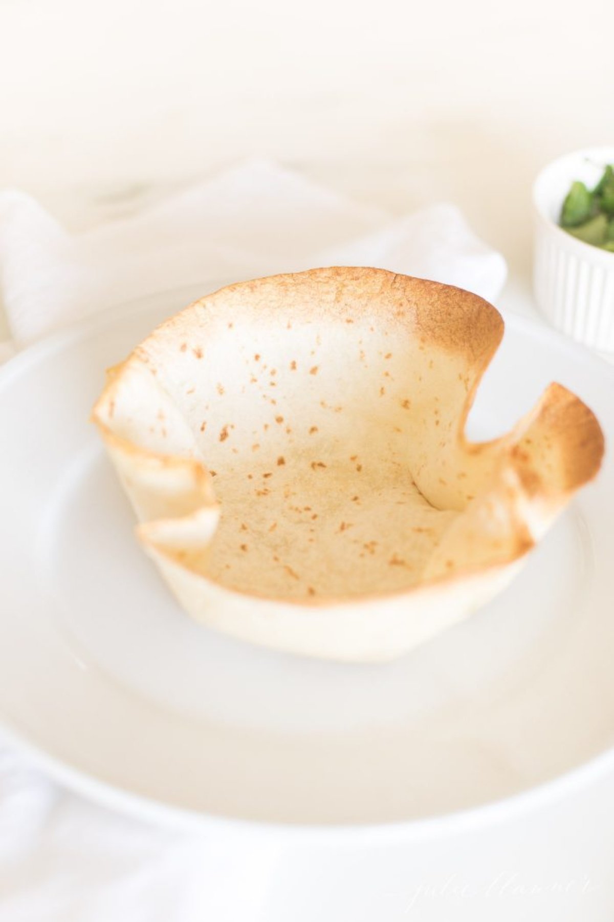 A taco salad bowl on a white plate.