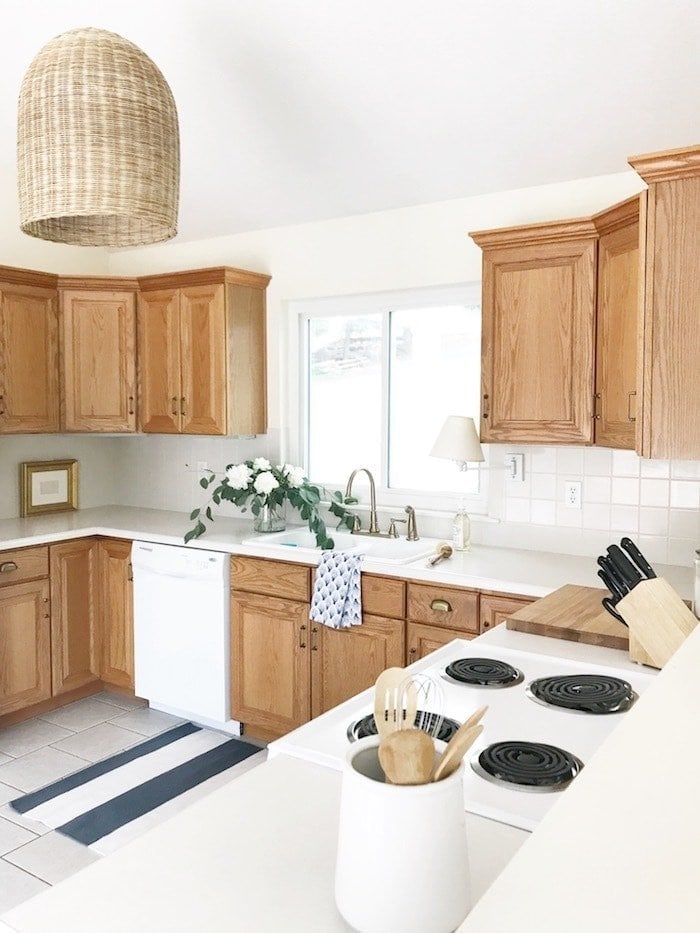 wood overlay cabinets in kitchen with pendant light and stripe rug