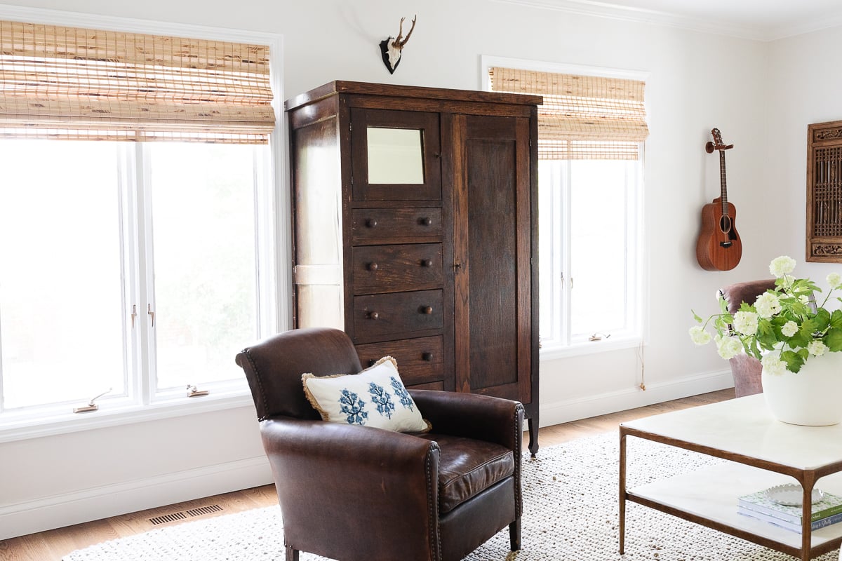 A kid friendly living room with a brown chair and a wooden cabinet.