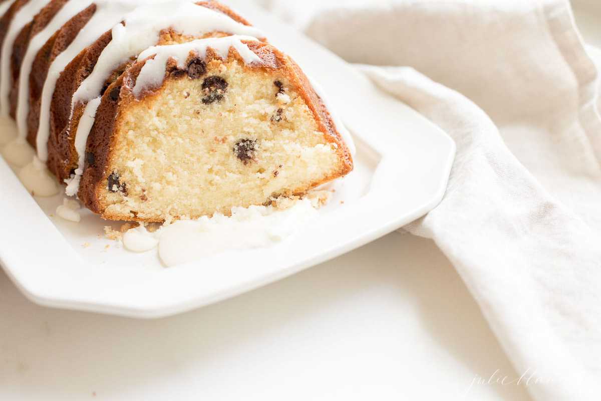 chocolate chip pound cake shaped in a decorative loaf, glazed with icing, resting on a white platter