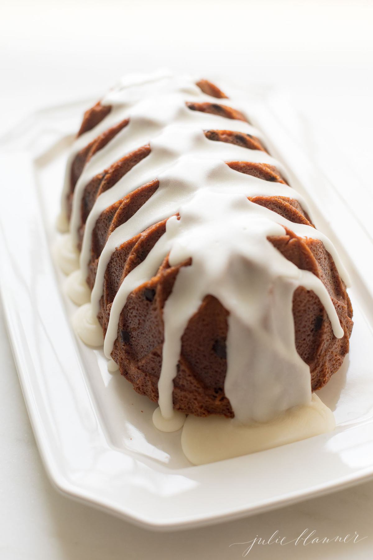 chocolate chip pound cake shaped in a decorative loaf, glazed with icing, resting on a white platter