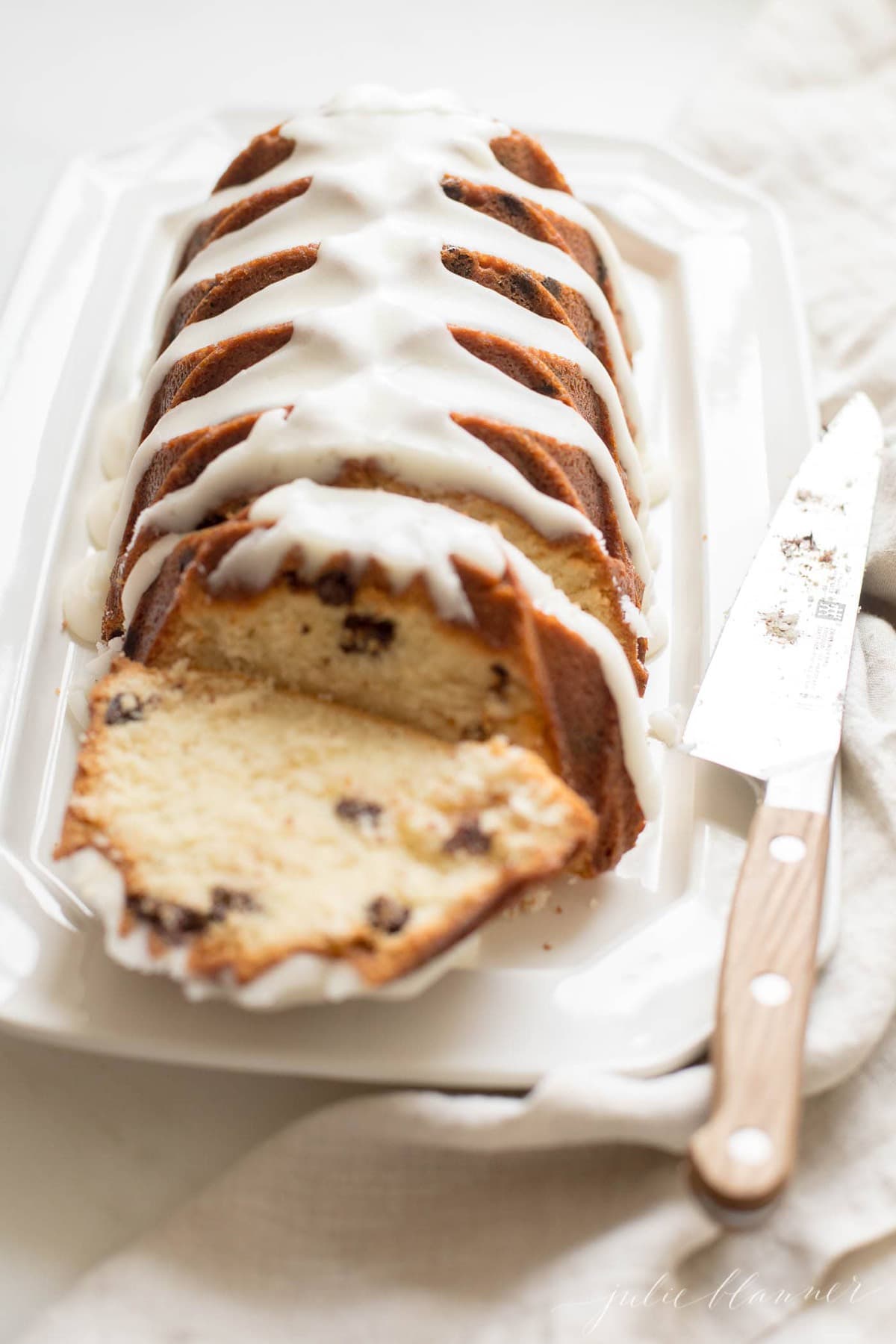 chocolate chip pound cake shaped in a decorative loaf, glazed with icing, resting on a white platter