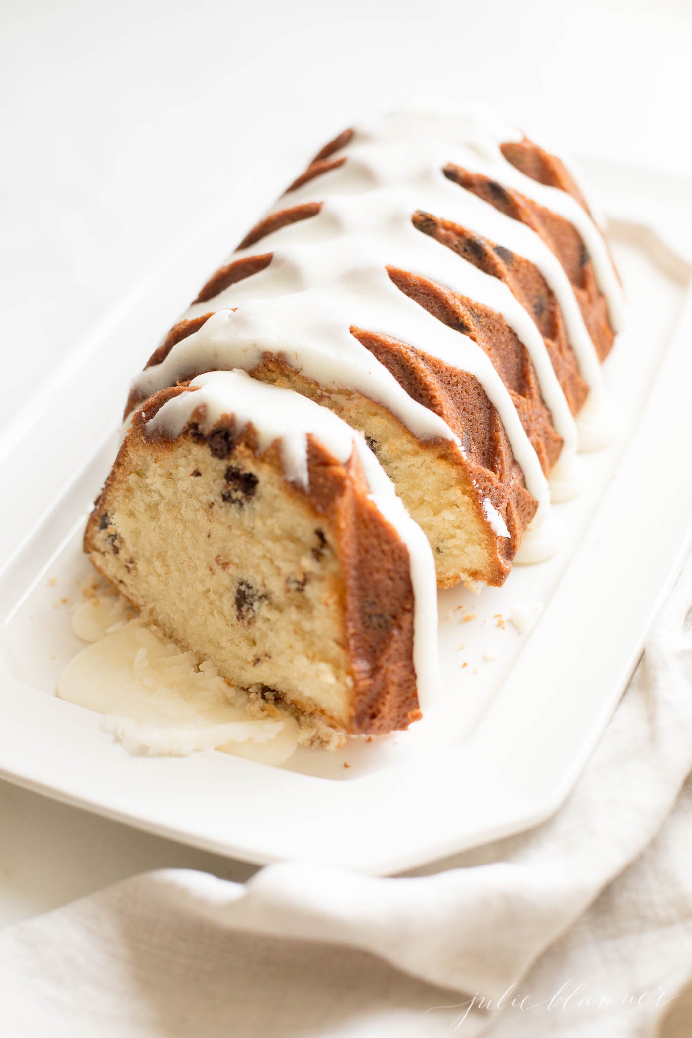 chocolate chip pound cake shaped in a decorative loaf, glazed with icing, resting on a white platter