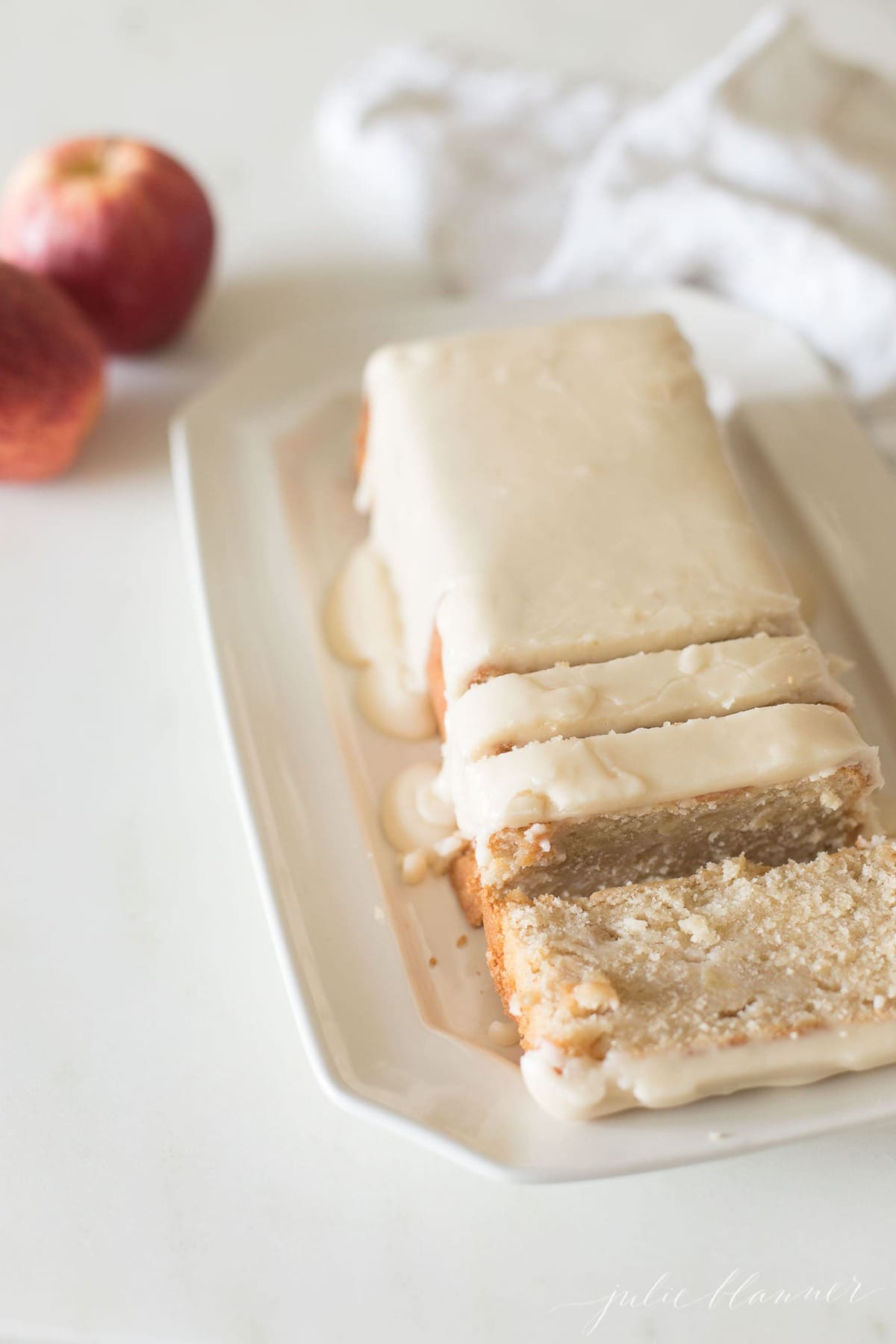 apple pound cake sliced on a white platter, covered in apple glaze