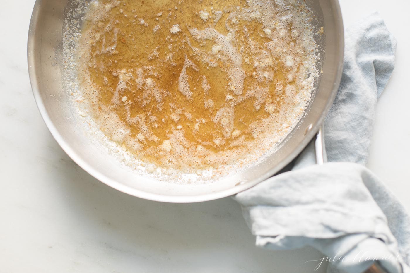 A silver pan with handle, warmed brown butter inside.