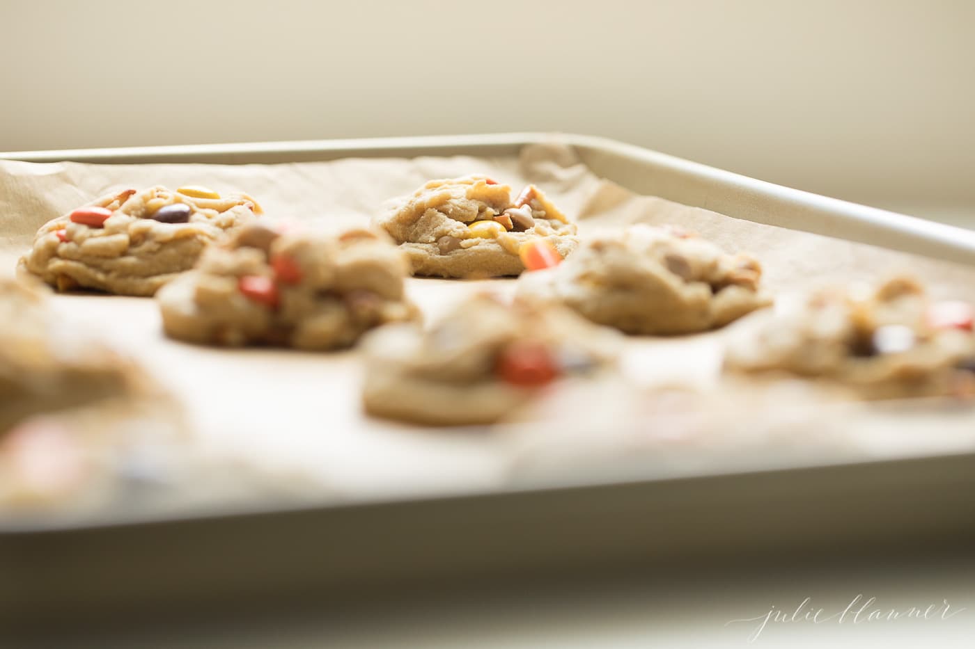 monster candy cookies on a gold sheet pan with parchment paper