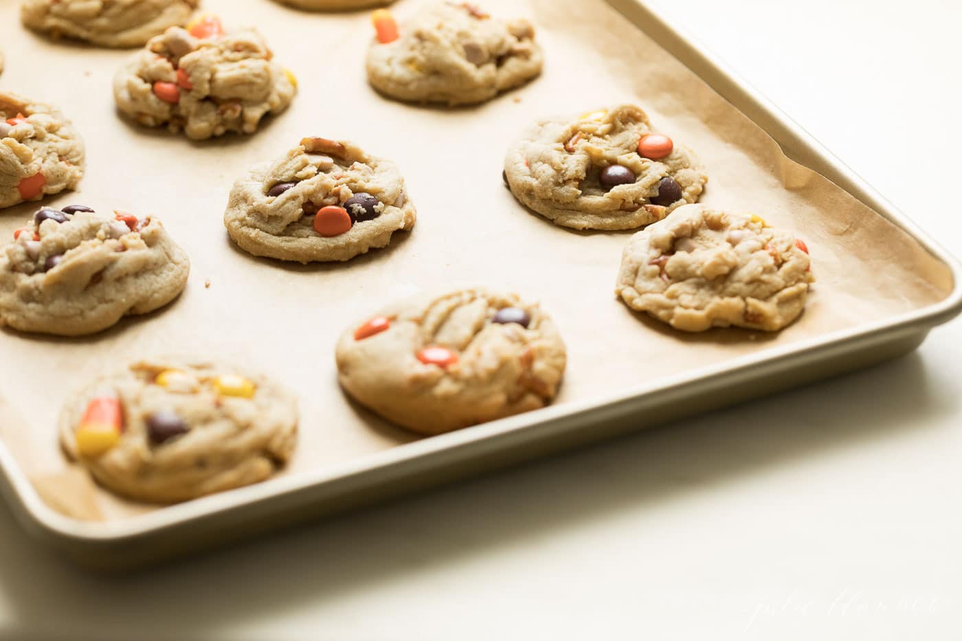 A gold sheet pan with monster cookies, candy corn and reese's candies peaking through.