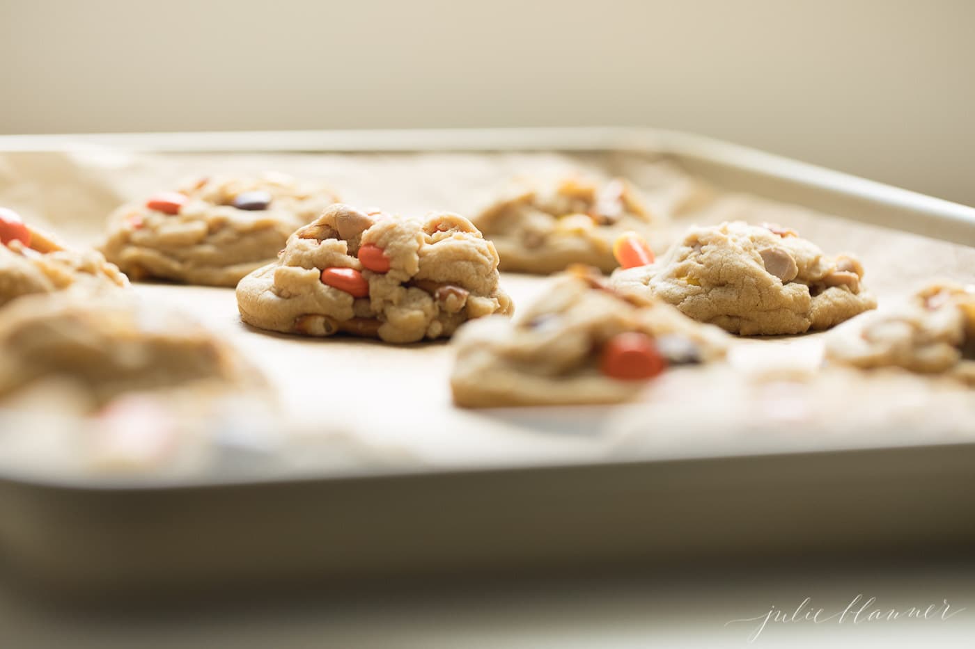 monster cookies on a gold sheet pan with parchment paper.