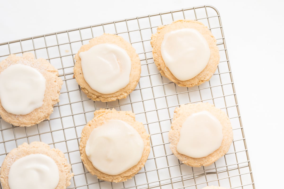 pumpkin sugar cookies with cream cheese glaze on a cooling rack
