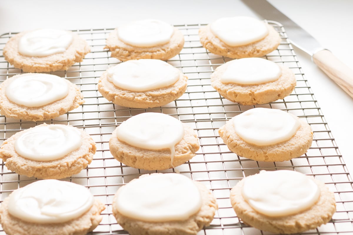 pumpkin sugar cookies with cream cheese glaze on a cooling rack