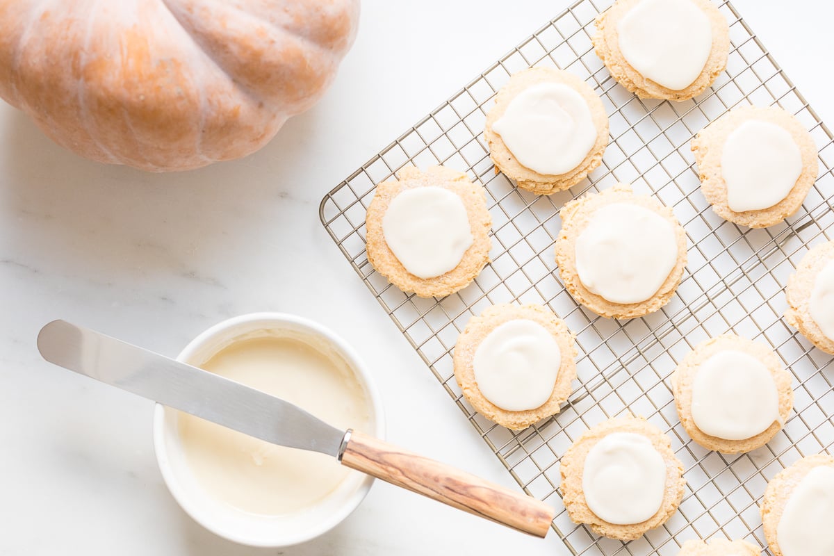 pumpkin sugar cookies with cream cheese glaze on a cooling rack