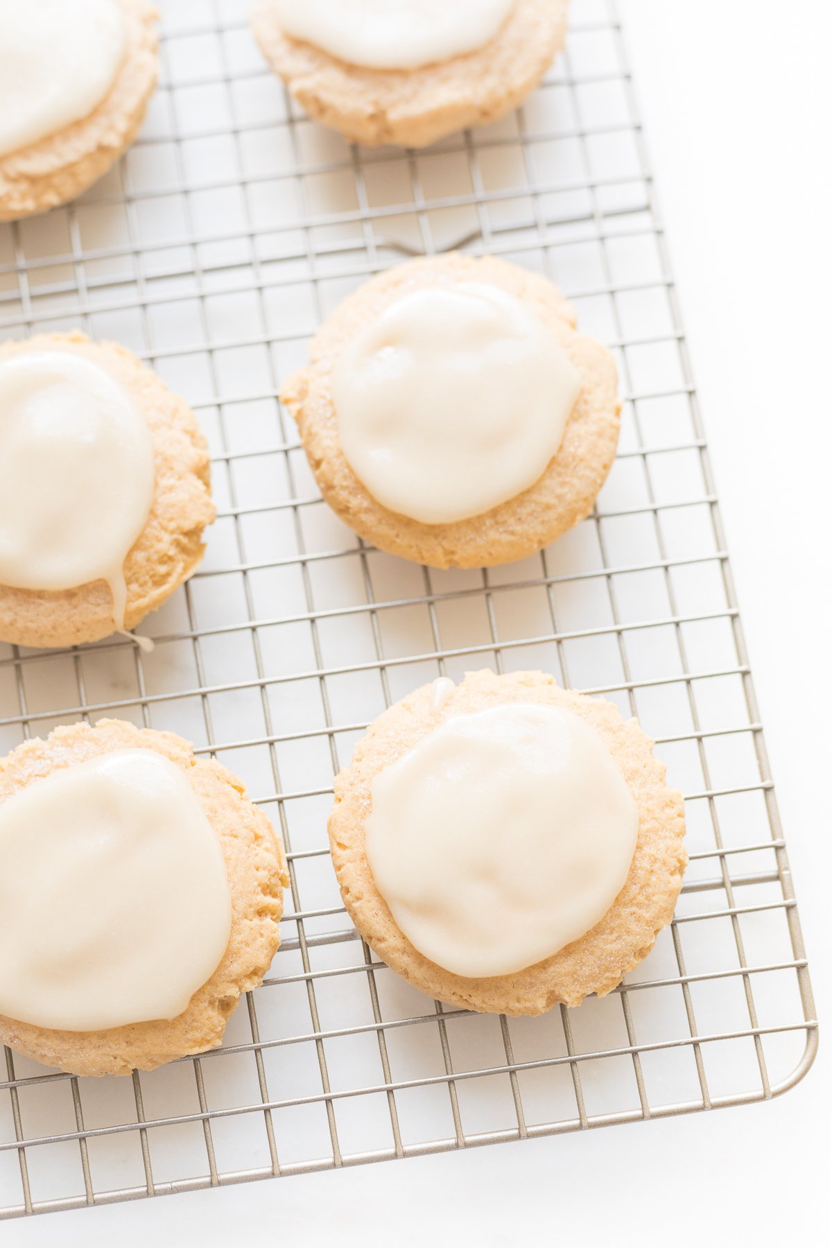 pumpkin sugar cookies with cream cheese glaze on a cooling rack