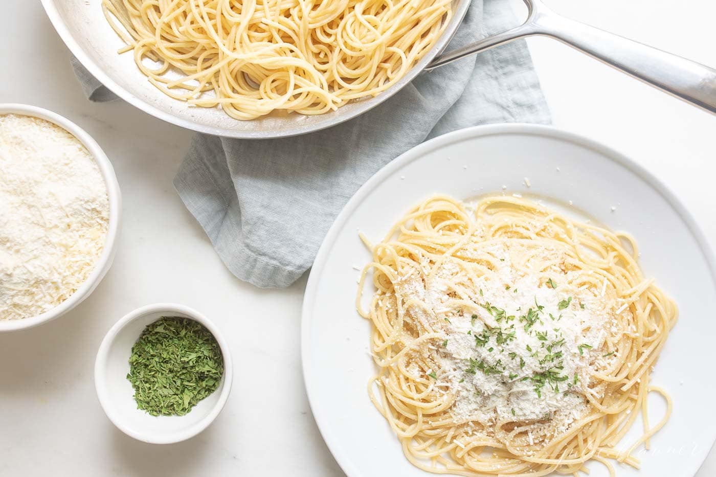 spaghetti with mizithra cheese on a plate and mizithra in a bowl