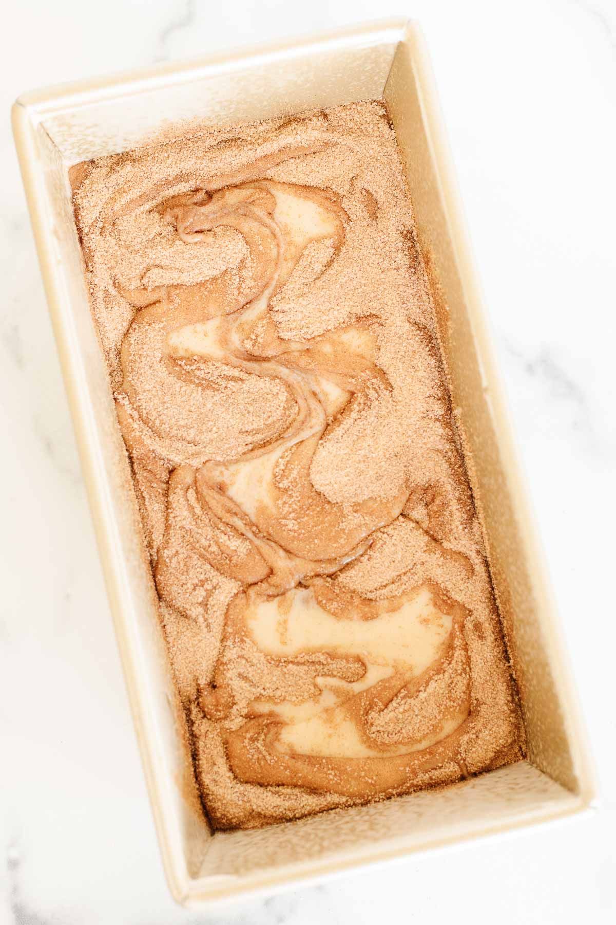 A cinnamon roll loaf in a gold loaf pan, before baking