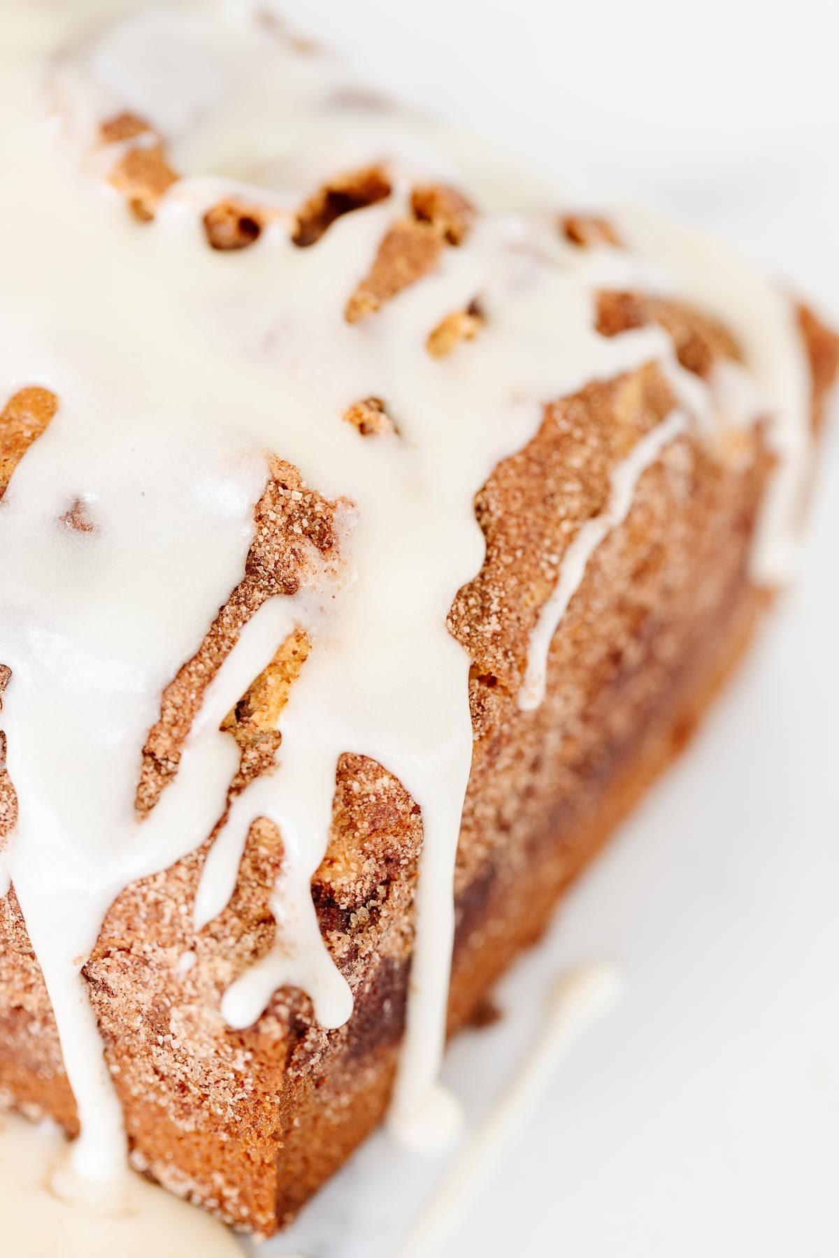 A loaf of cinnamon roll bread, drizzled with icing on a marble countertop