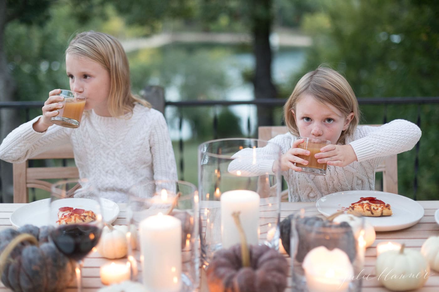 kids eating pizza and drinking apple cider at an outdoor dining table