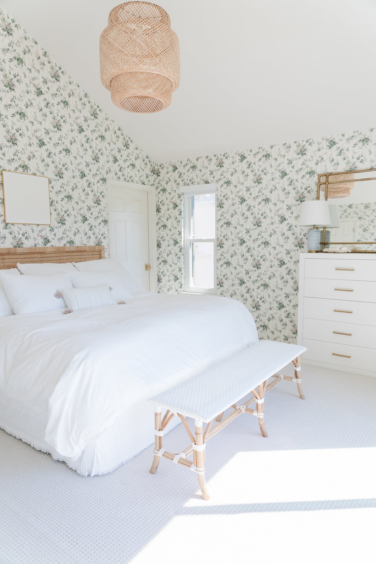 A bedroom with floral wallpaper and wall to wall carpeting.