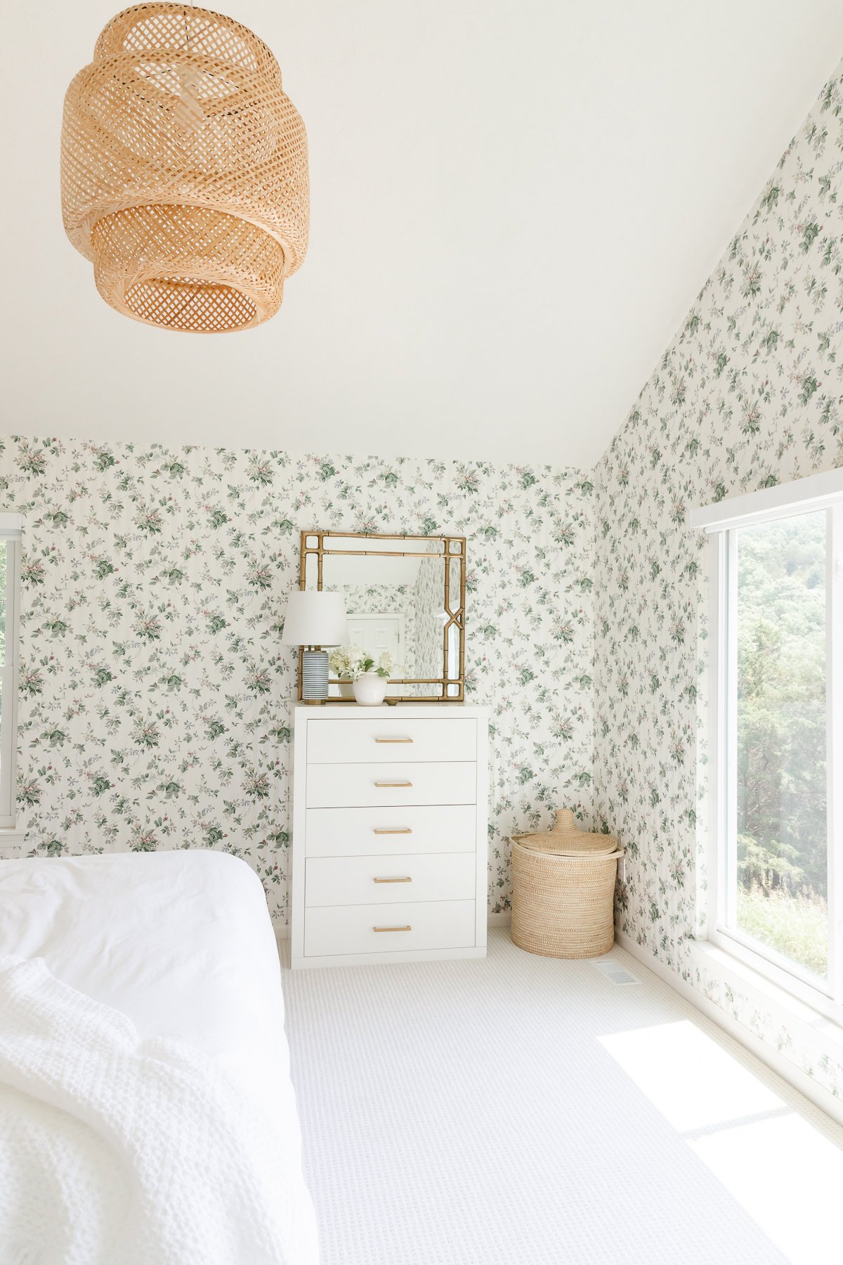 A bedroom with floral wallpaper and wall to wall carpeting.