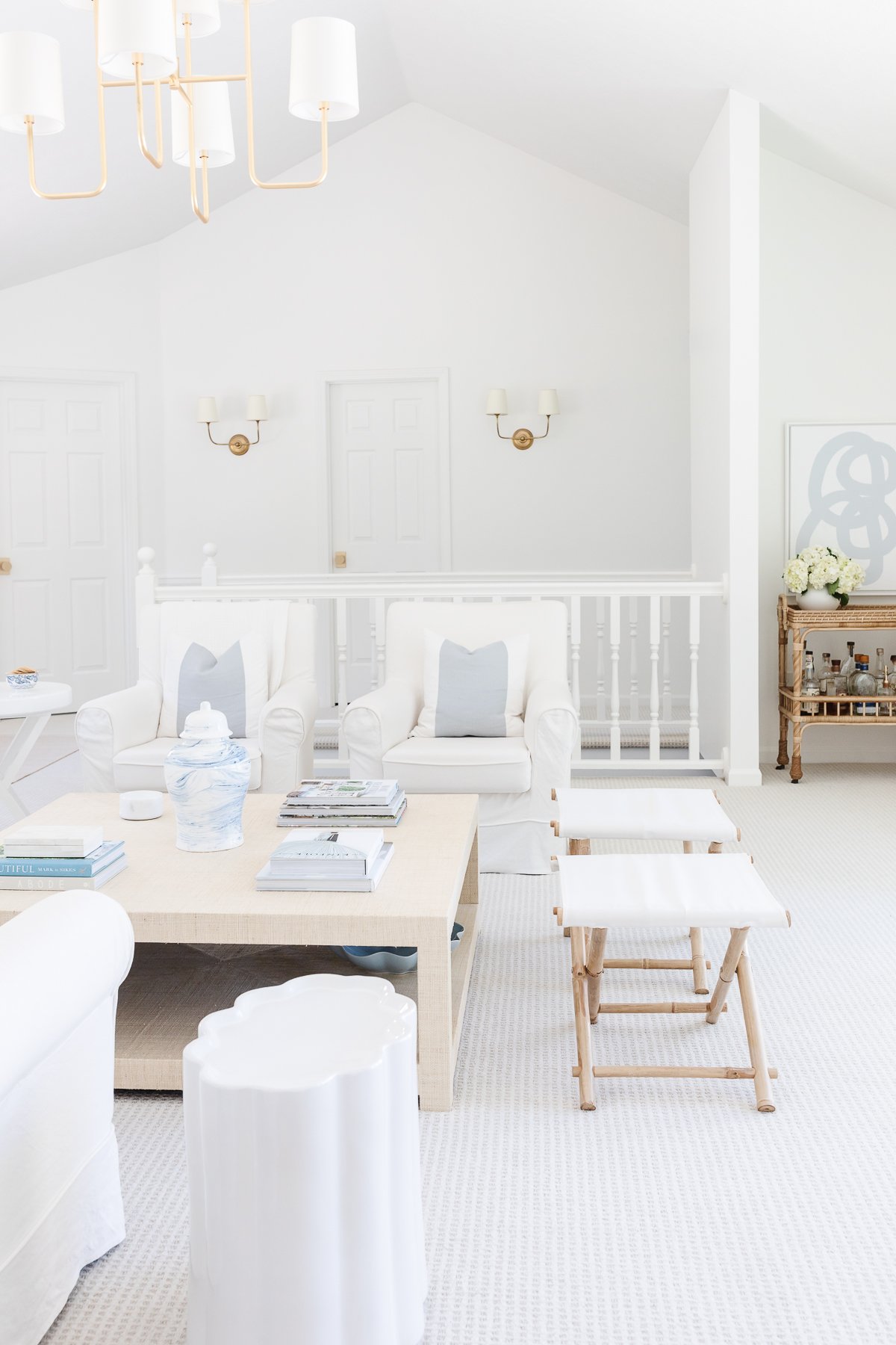 A white living room with white furniture and wall to wall carpet.