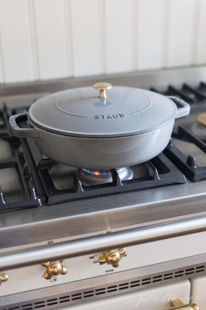 A gray cast iron saute pan with lid on a french range.