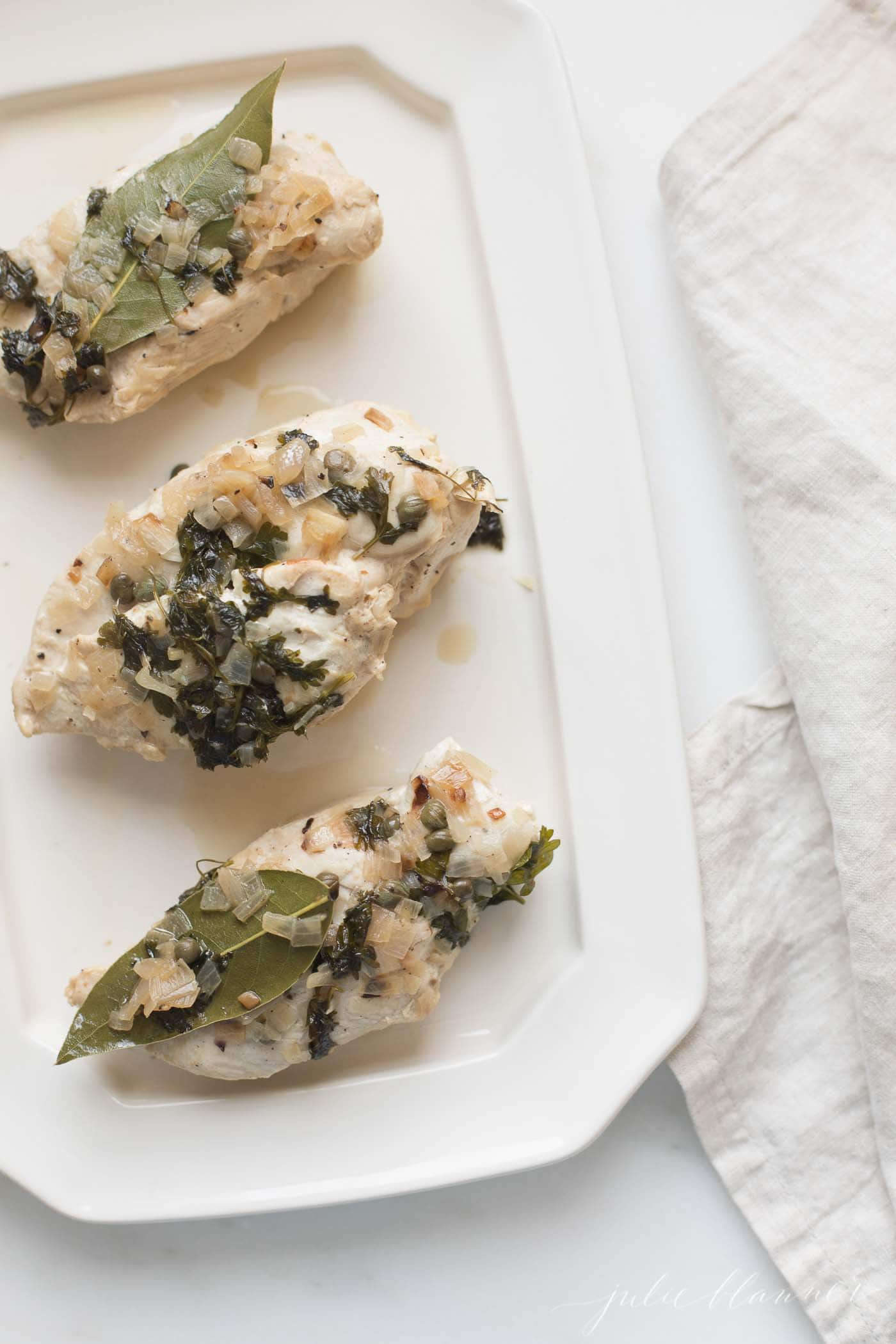 chicken with herbs in white wine sauce on platter