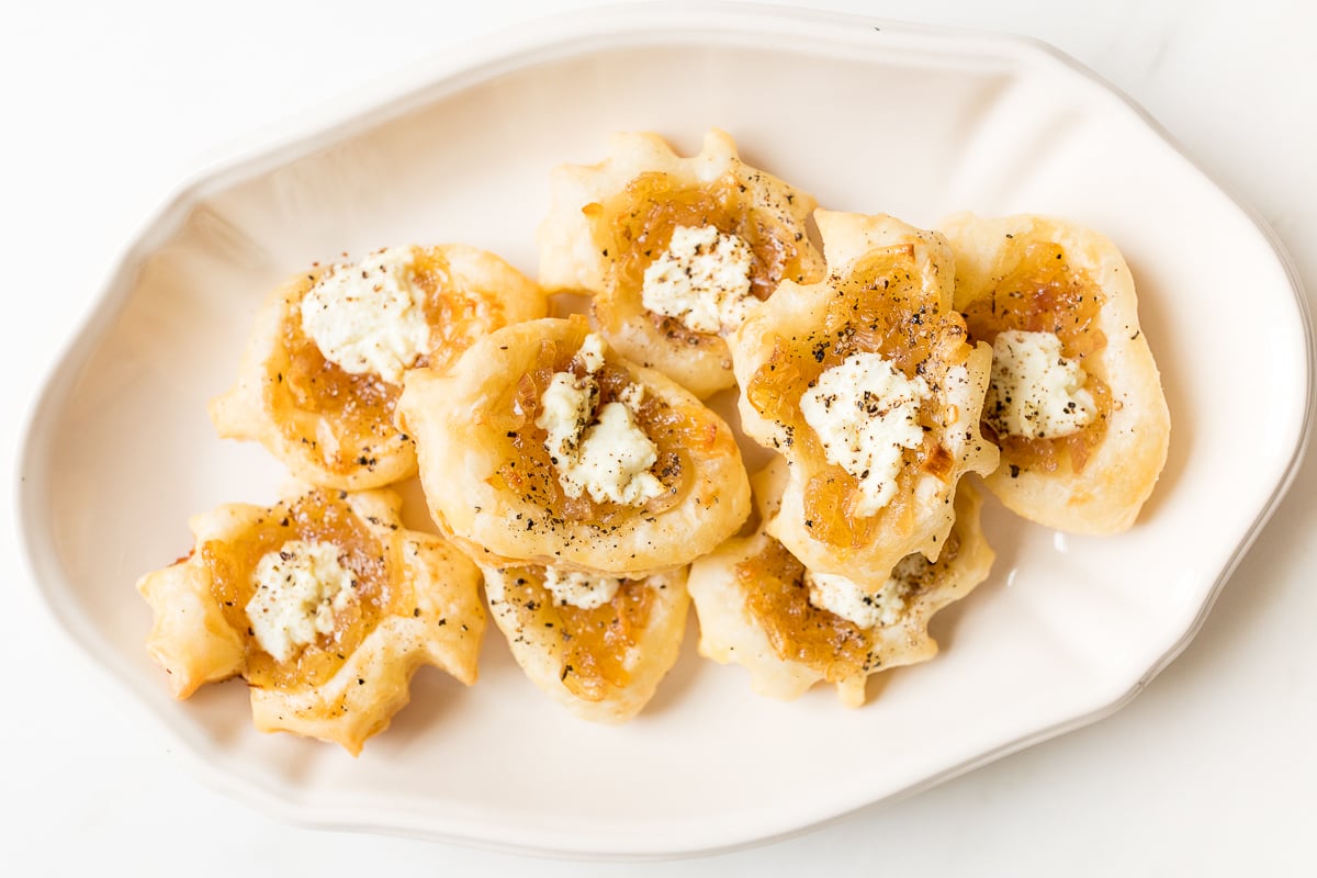 Caramelized shallot tarts on a white platter.