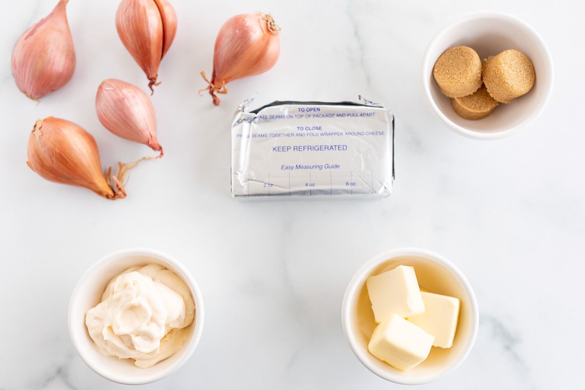 Ingredients for a dip recipe with caramelized shallots laid out on a marble surface