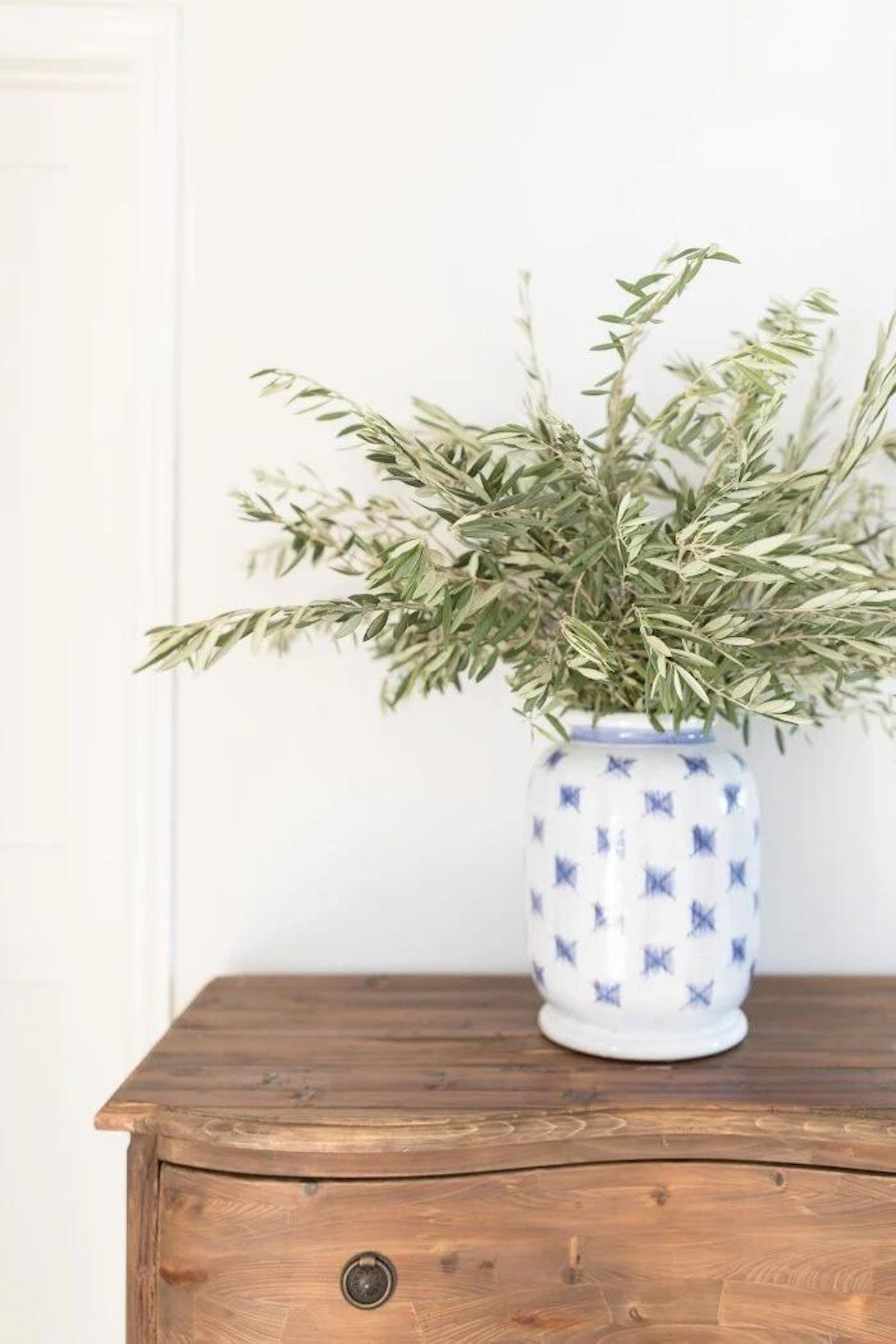 A blue and white vase sits on a wooden dresser in a house.