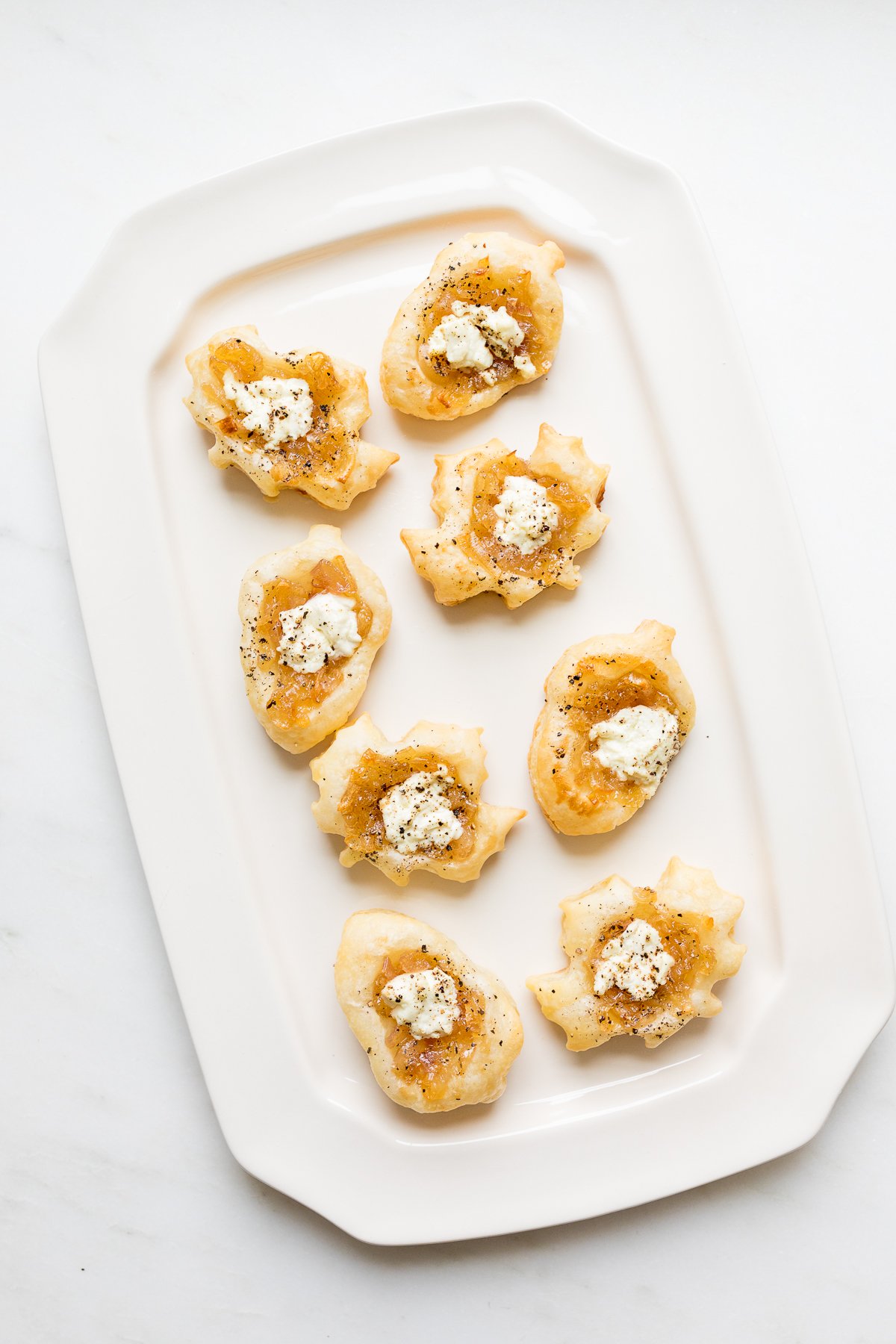 Caramelized shallot tarts on a white platter.