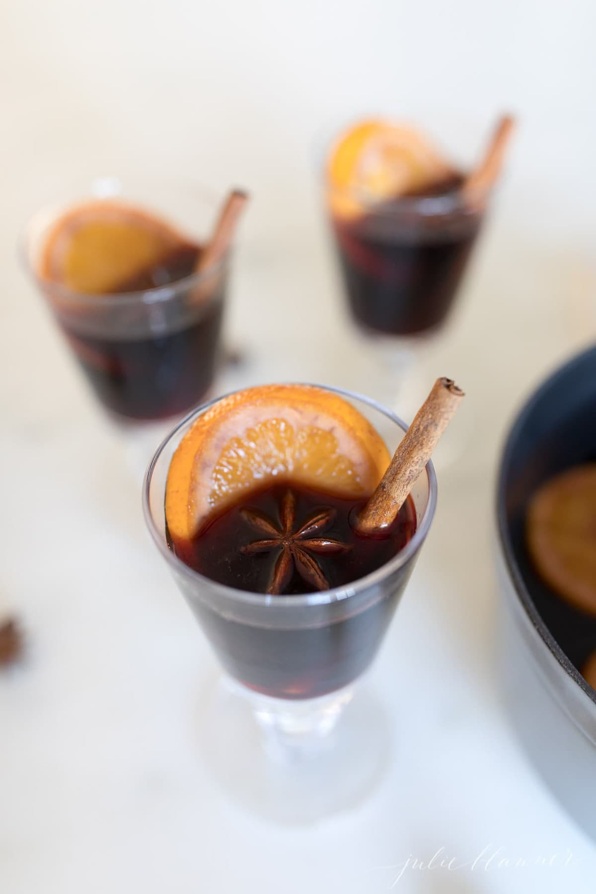 three glasses of non alocholic mulled wine with orange slice, star anise, cinnamon stick