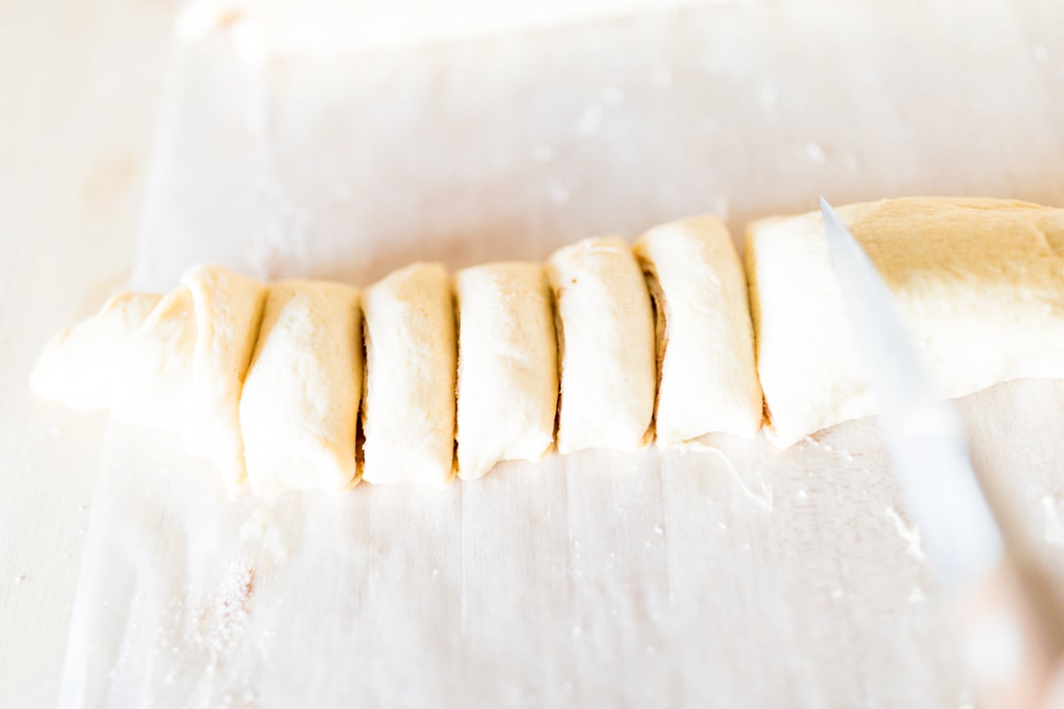 A person cutting pecan rolls.