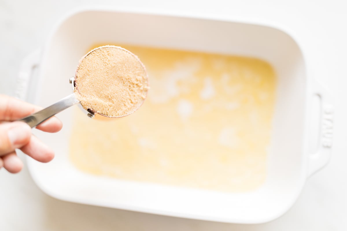 A person sprinkling sugar onto pecan rolls.