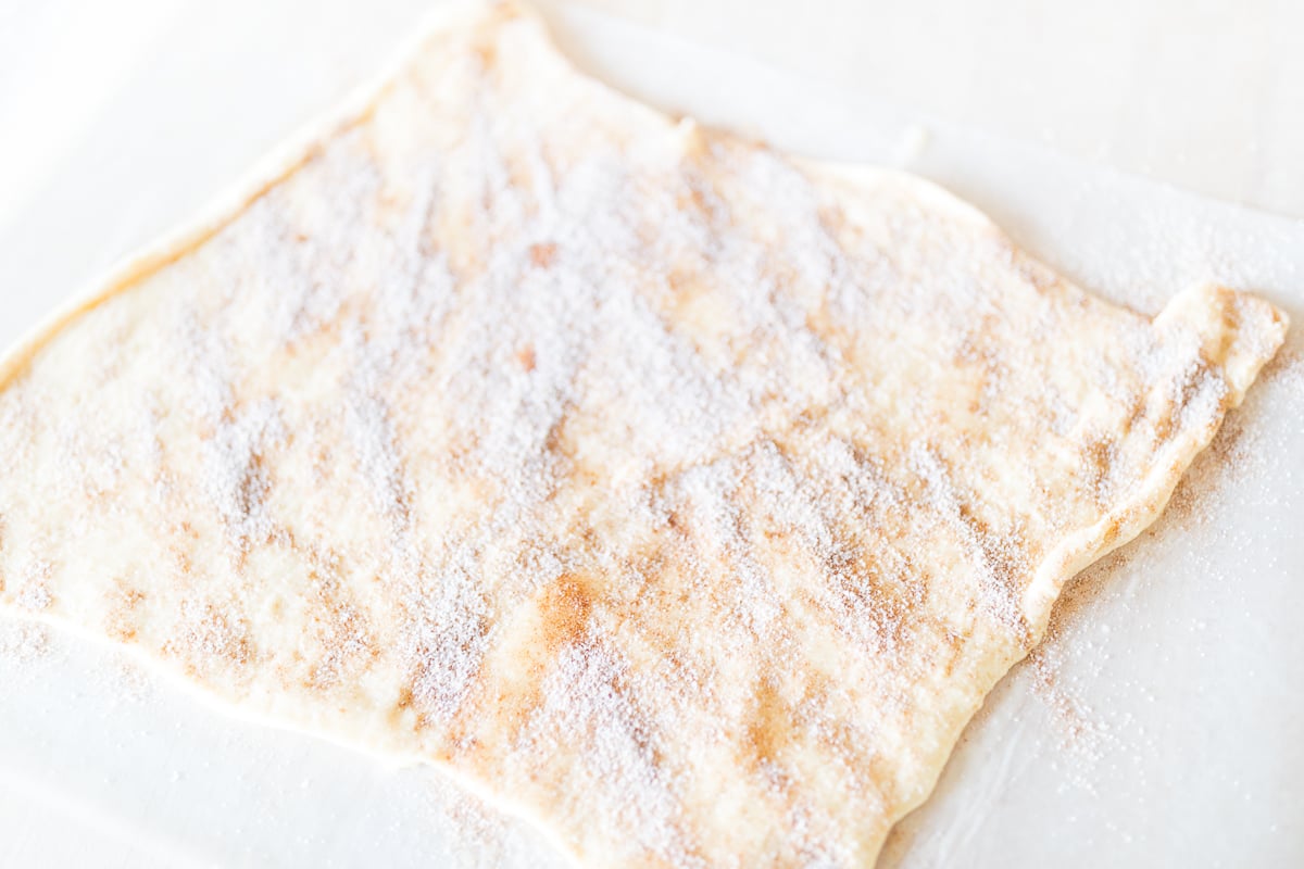 A piece of pecan roll dough topped with powdered sugar.
