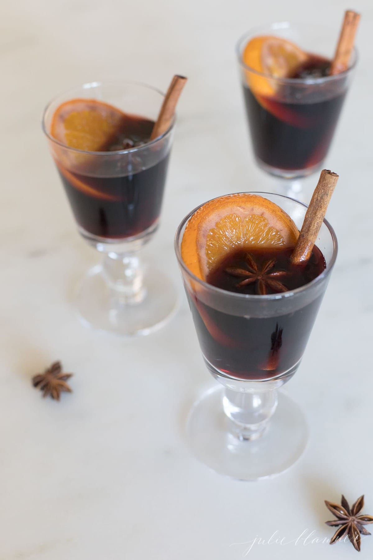 three glasses of non alocholic mulled wine with orange slice, star anise, cinnamon stick