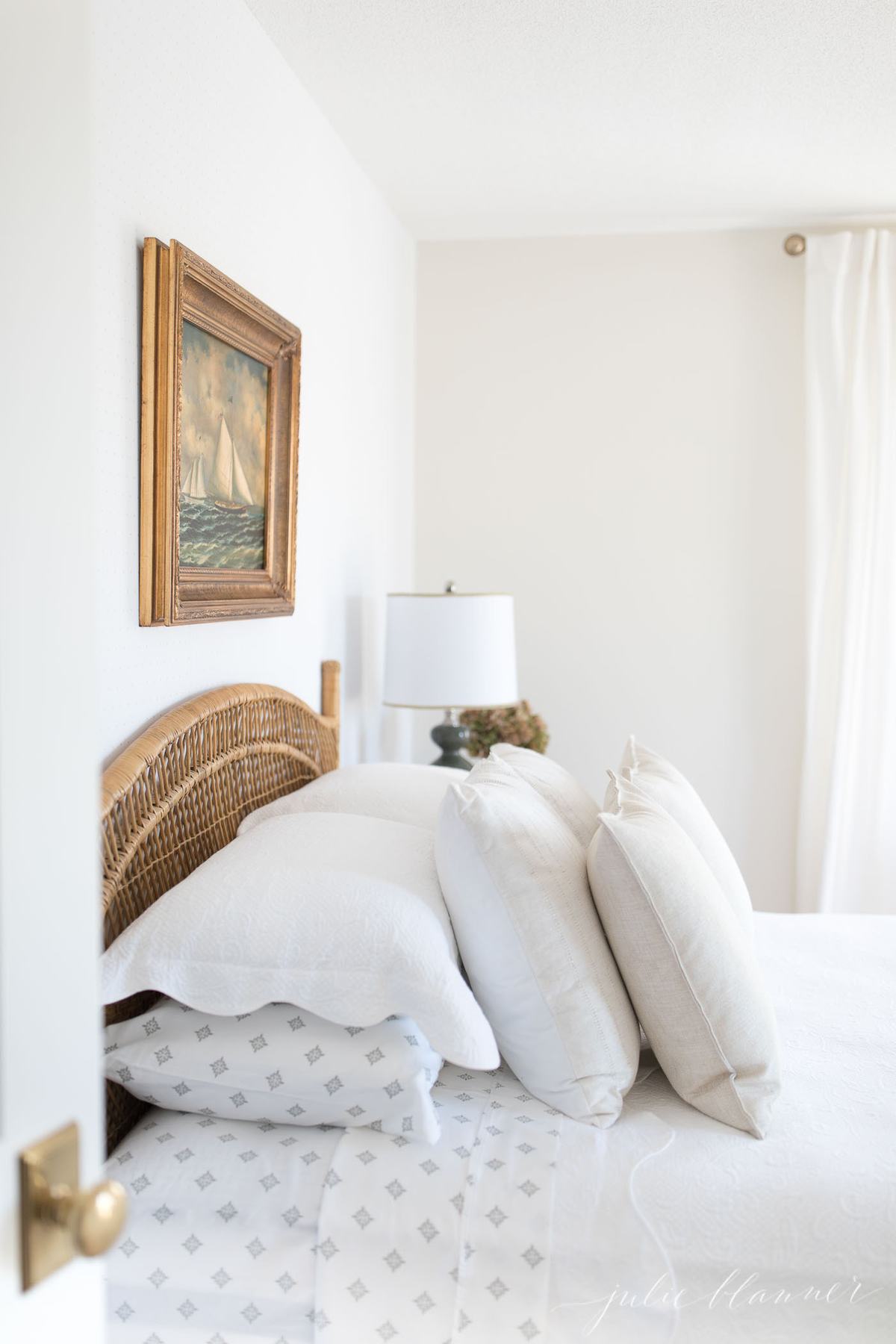 door opened to traditional bedroom with bed, pillows and painting above 