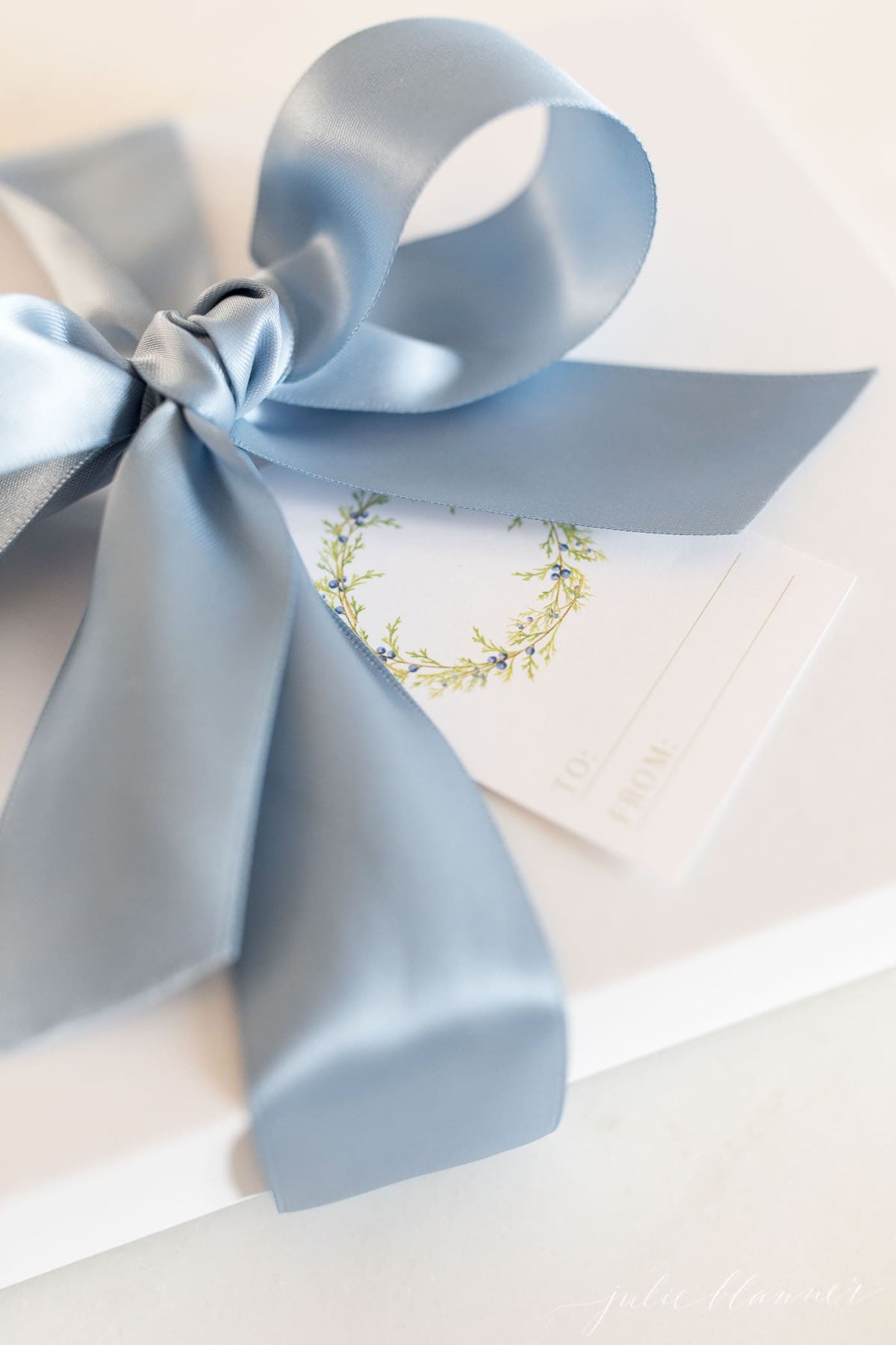 free printable christmas gift tags with a green wreath on a white package tied with blue satin ribbon.